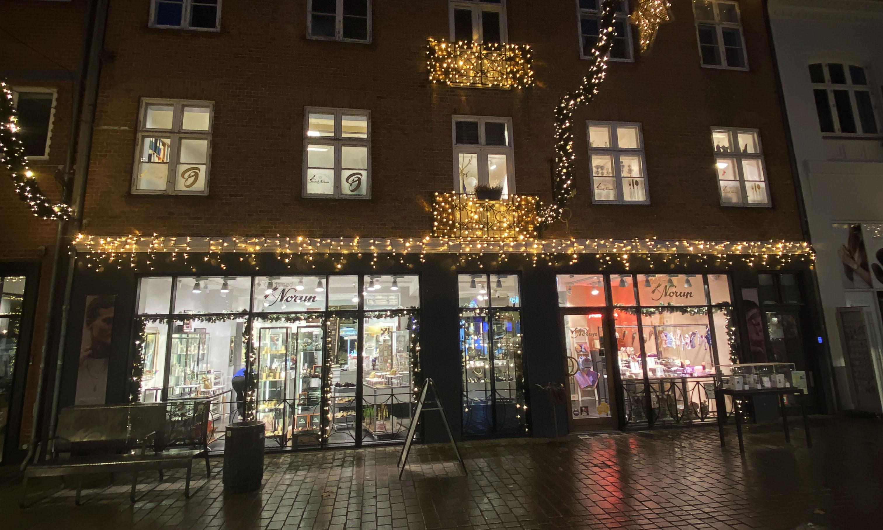 En smuk bygning med julelys og dekorationer, der lyser op i natten på en hyggelig gade.