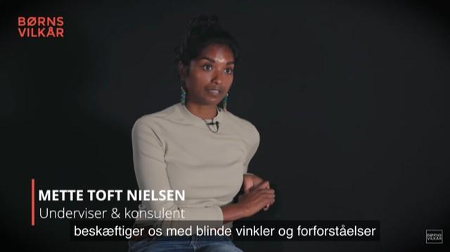 Mette Toft Nielsen sidder i en sort baggrund og taler om blinde vinkler og forforståelser som underviser og konsulent.