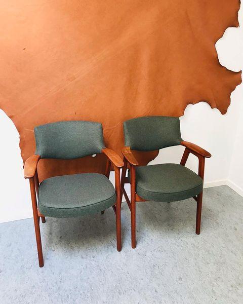 To sæt af grønne stole med træarmlæn foran en lædervæg. Stolene har en enkel og moderne design.