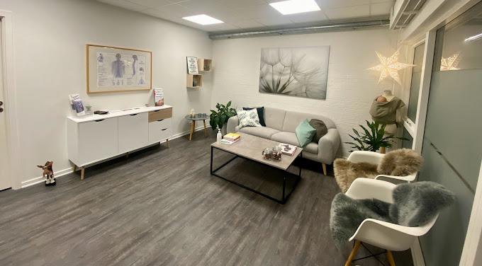 Lyst og moderne opholdsrum med sofa, bord, planter og kunstværker på væggene.