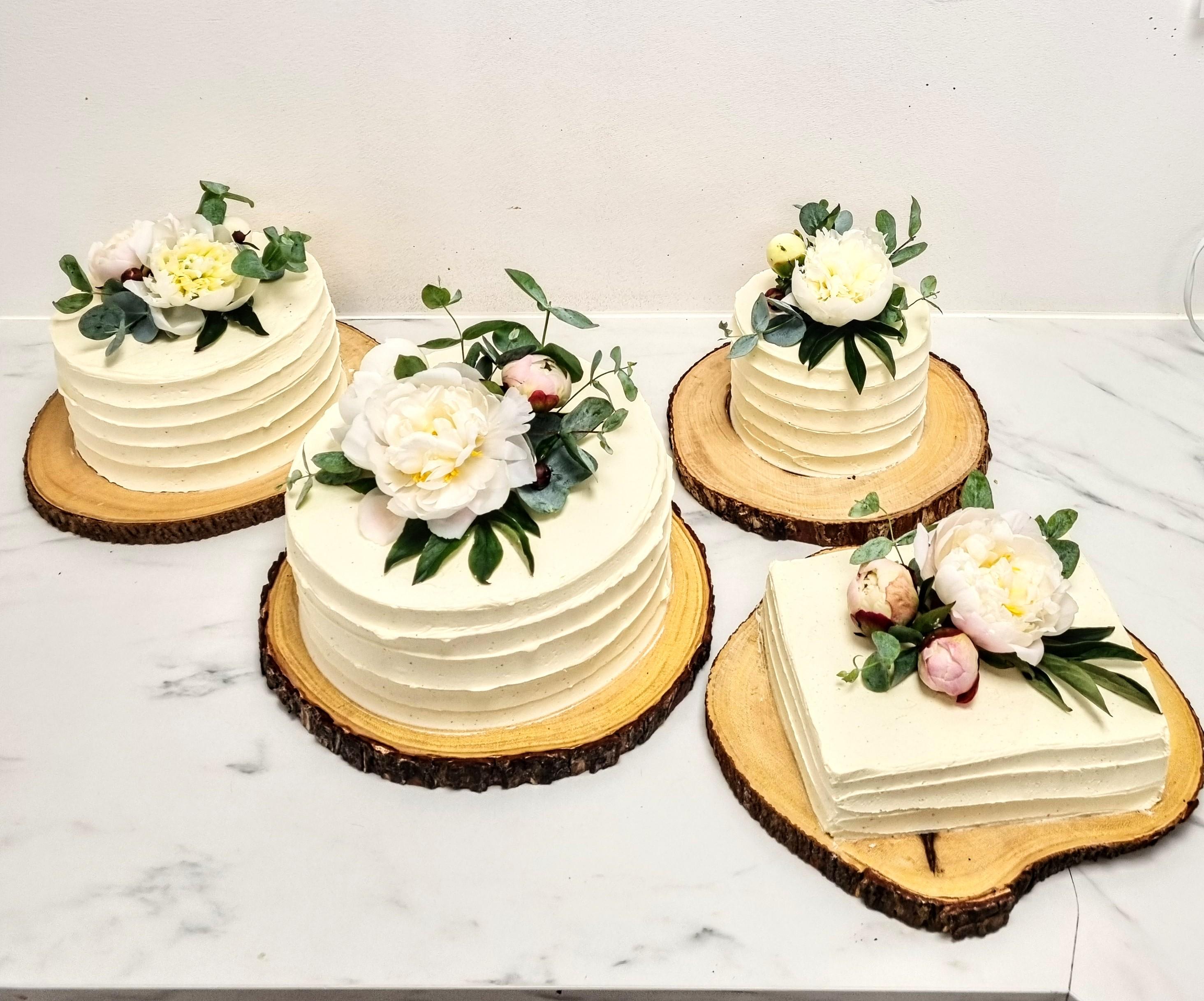 Flotte kager med flødeskum og blomsterdekorationer på træskiver.