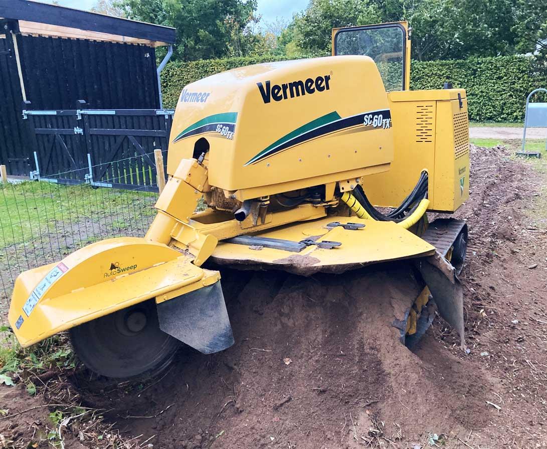 Gul stubbefræsser fra Veitmeer, der arbejder på en jordbunke i en have.