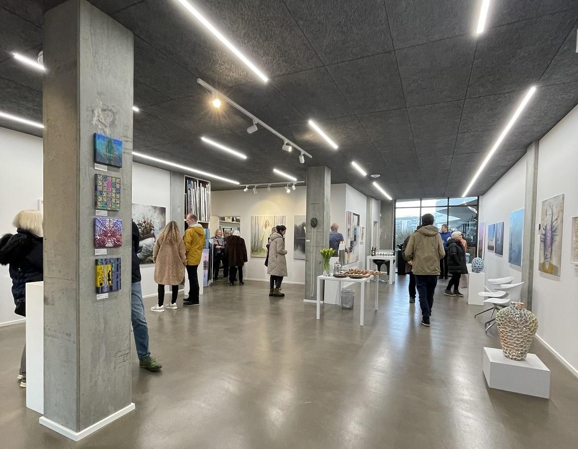 Moderne kunstgalleri med besøgende, vægge prydet med malerier og skulpturer, samt en lys og åben atmosfære.