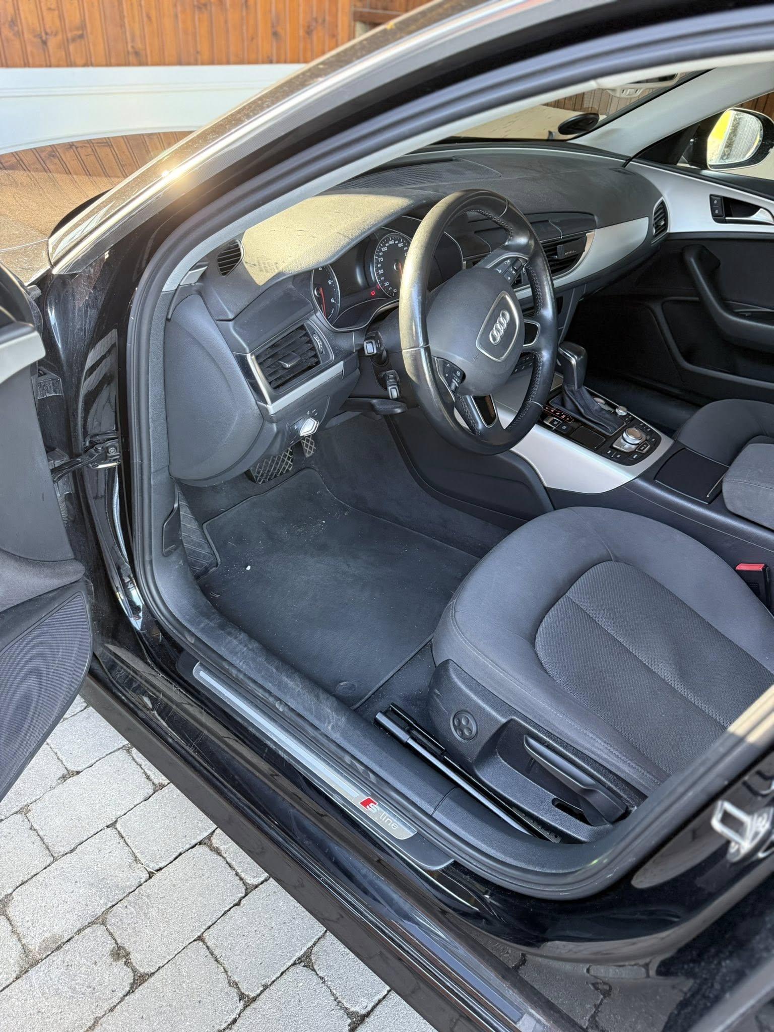 Billede af indersiden af en sort Audi med stofsæder og moderne instrumentbræt.