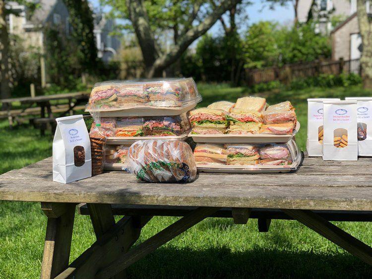 Lækre sandwich og bagværk præsenteret på et træbord i en grøn park.