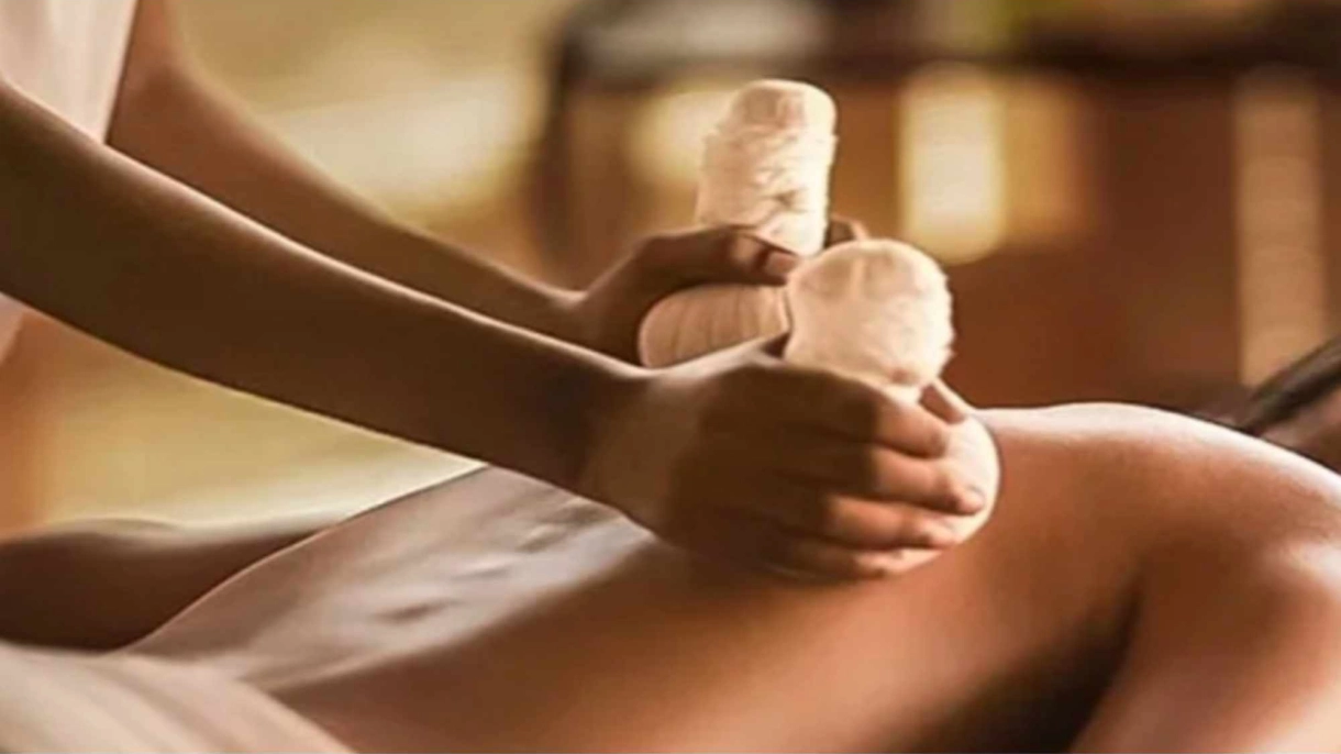 En person får en afslappende massage med varme urtepuder på ryggen.