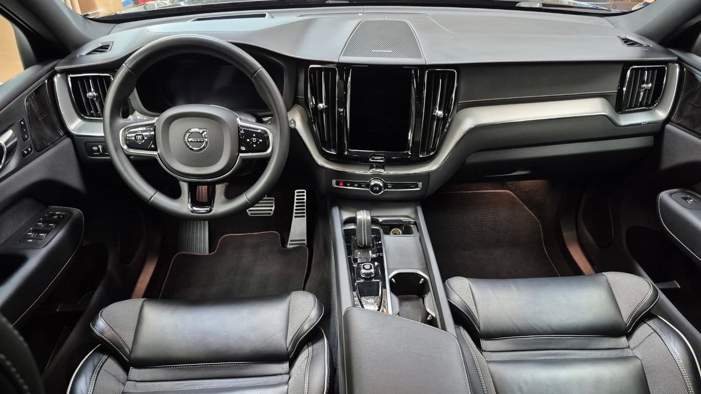 Interiør af en Volvo bil med sort læder sæder, moderne dashboard og stor touchscreen i midten.