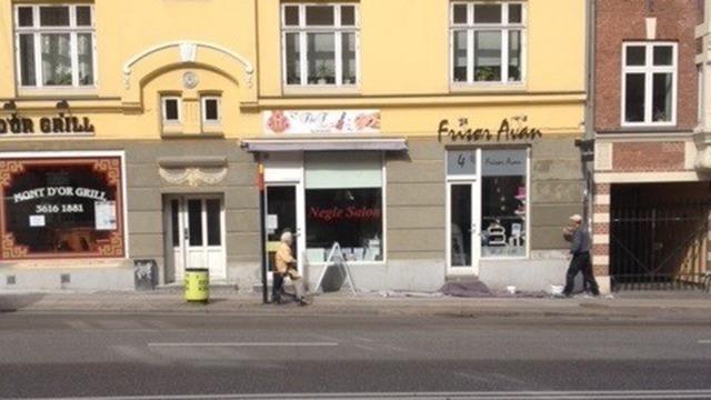 Butiksvinduer med skilte og en person, der går forbi på gaden i en by.