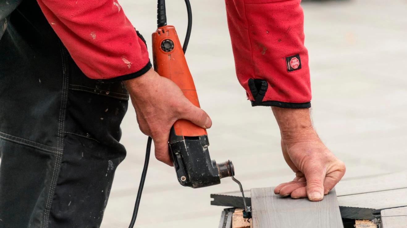 Håndværker bruger en elektrisk sav til at skære fliser på en byggeplads.