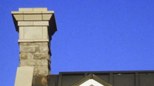 Skorstenen på et hus med en klar blå himmel i baggrunden.