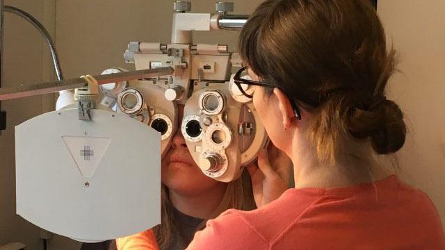En optiker undersøger en patients syn med en synsprøvemaskine i et klinisk miljø.