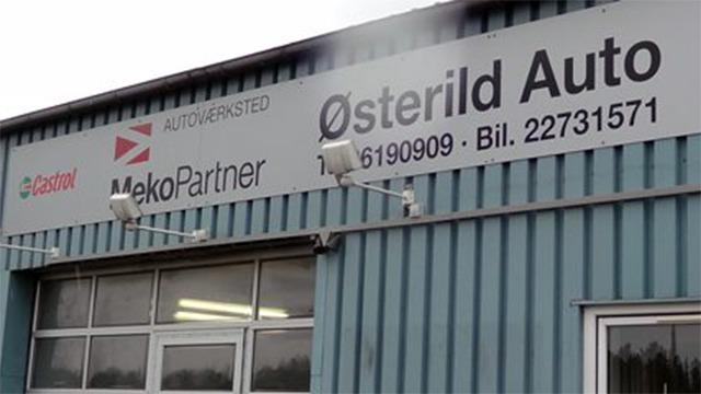 Skilt med teksten "Østerild Auto" og "MekoPartner" på en blå metalbygning.