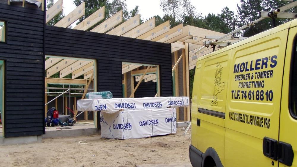 Byggeri af et hus med træramme og en varevogn fra Møllers Snedker & Tømrer foran.