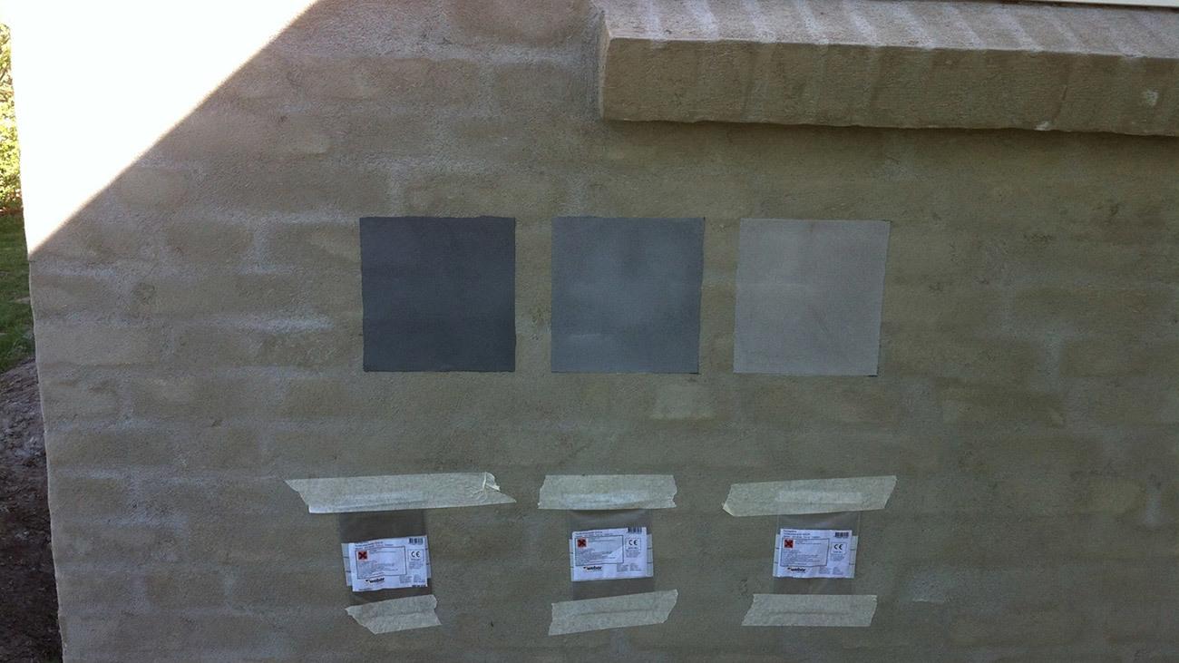 Farveprøver på en mur med tre forskellige nuancer og tape, der holder dem på plads.