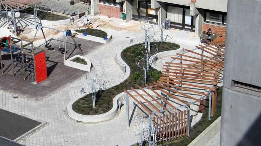 En moderne bypark med snoede stier, træer, bænke og legepladsudstyr under konstruktion.