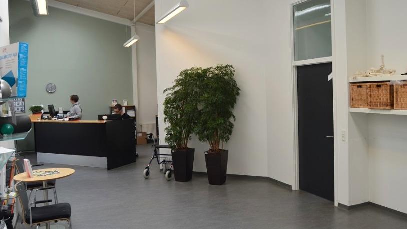 Indendørs kontormiljø med reception, planter og moderne indretning.