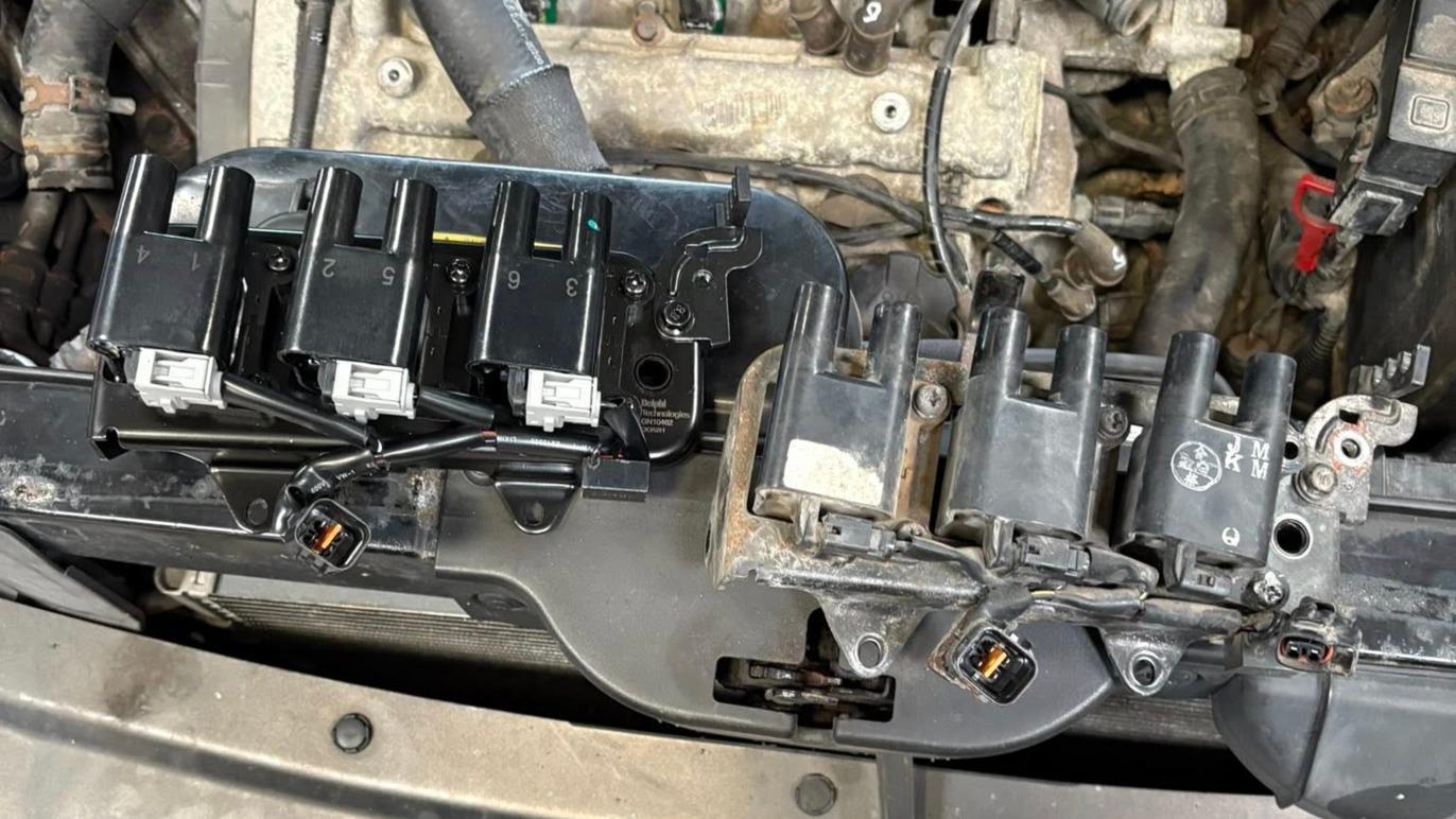 Billede af en motor med tændspoler og ledninger synligt monteret på motorblokken.