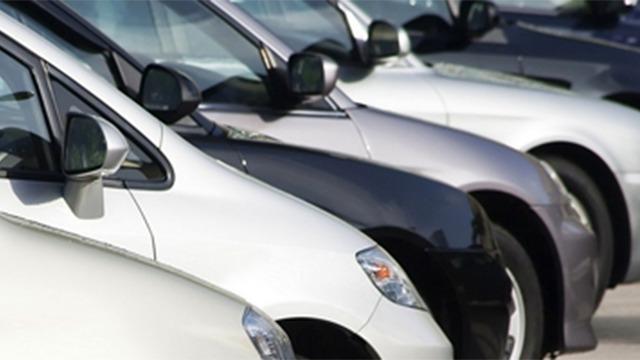 Række af biler i forskellige farver parkeret på en parkeringsplads.