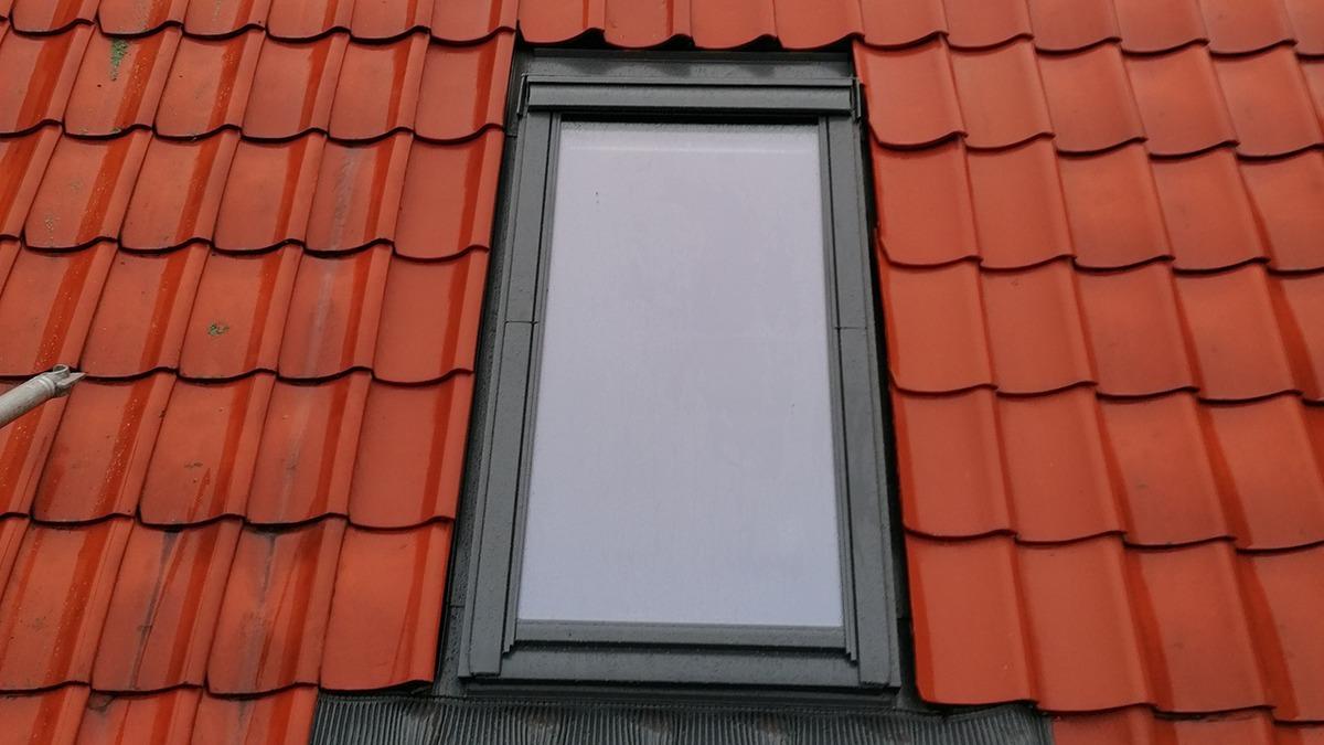 Tagvindue på et rødt tag med tagsten, der viser en klar himmel.