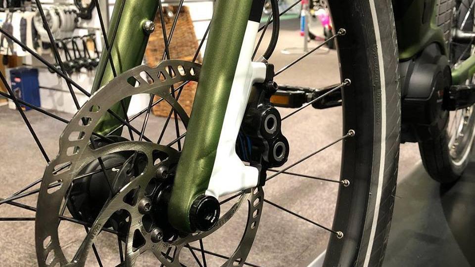 Nærbillede af en cykelbremse med skivebremse og grøn gaffel i en cykelbutik.