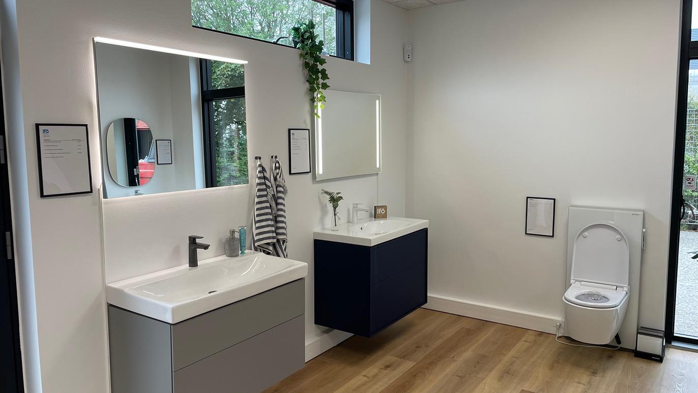 Moderne badeværelse med håndvask, spejl, toilet og trælook gulv. Minimalistisk indretning med planter.