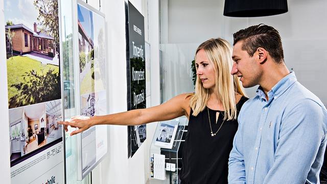To personer, en mand og en kvinde, ser på boligannoncer i et moderne kontor.
