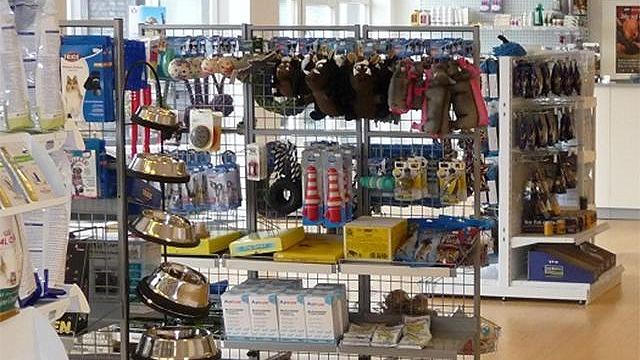 Butik med dyreudstyr, herunder skåle, legetøj og tilbehør til kæledyr på hylder.