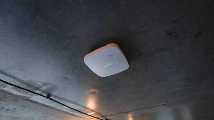 En moderne loftsmonteret Wi-Fi-router med LED-indikatorer i et rum med betonloft.