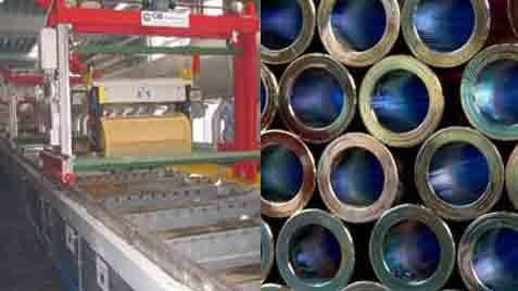 Industrielt produktionsanlæg med maskiner og metalrør stablet i en række.