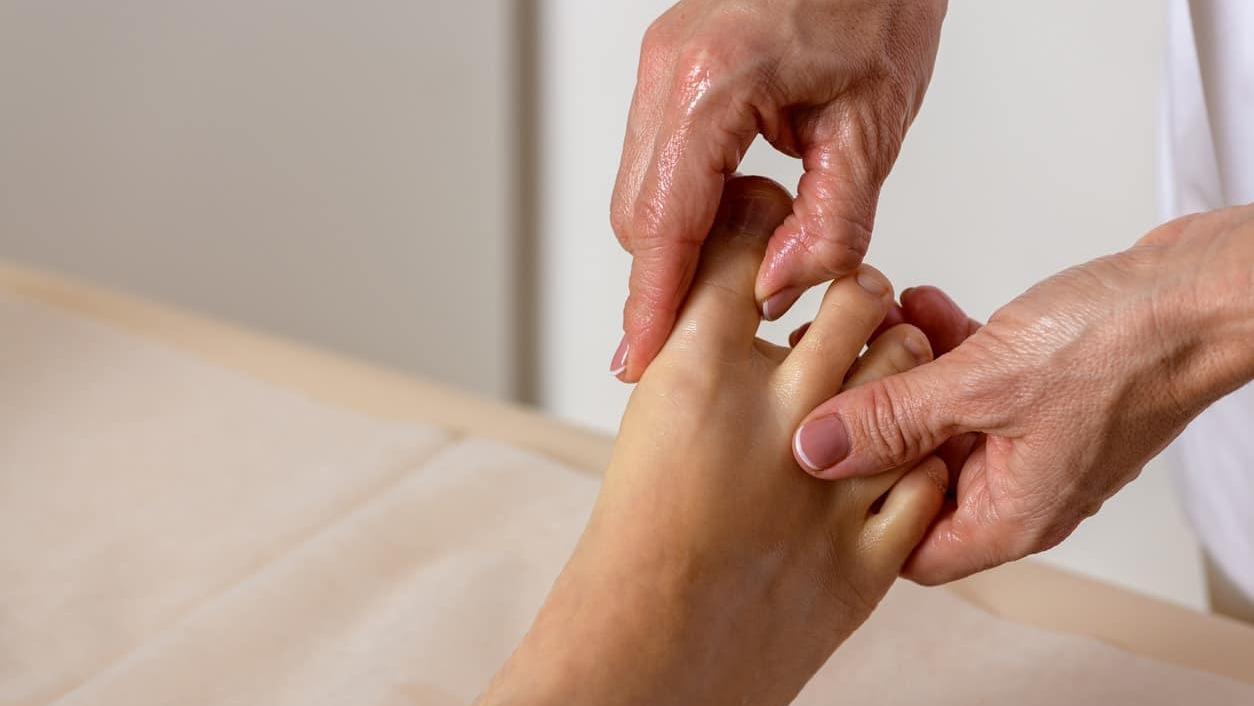 En hånd, der masserer en fod med fokus på afslapning og velvære.