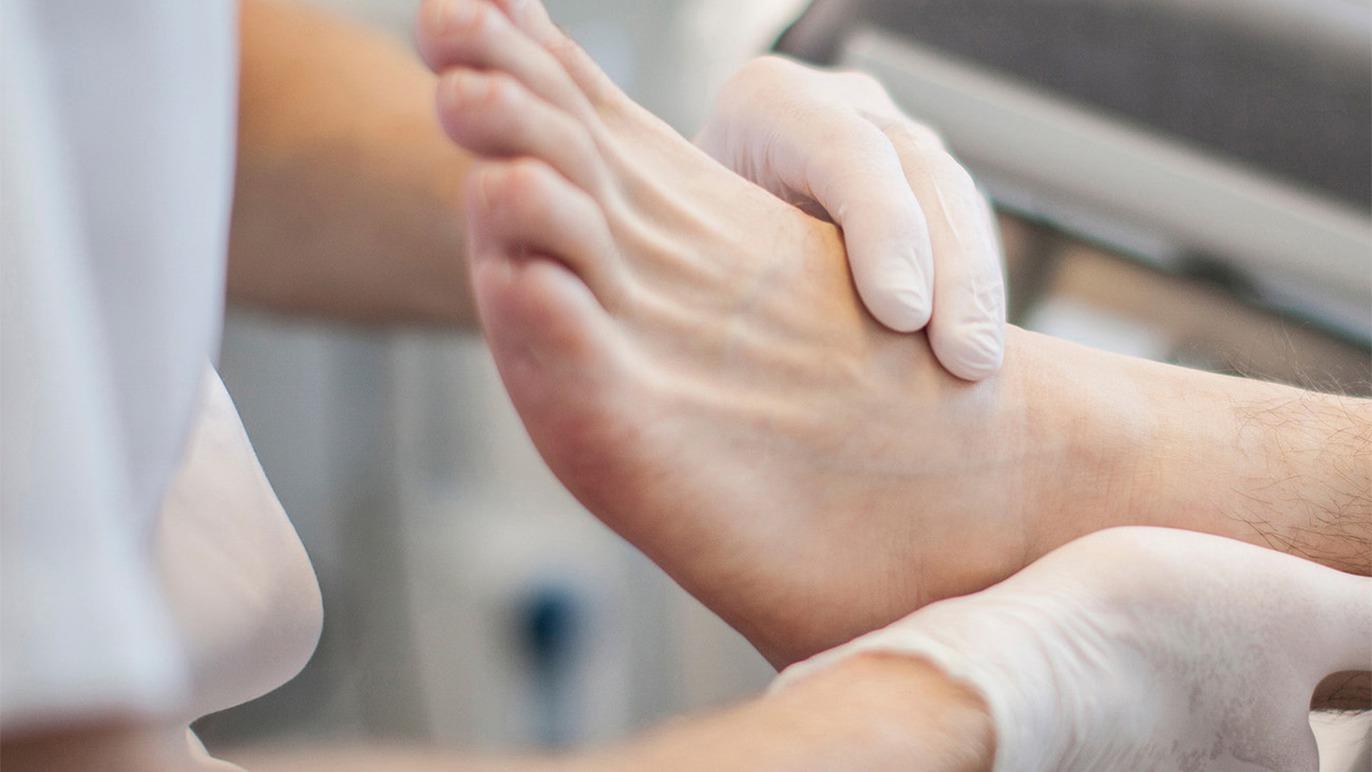 En person får fodmassage af en behandler med handsker på i en klinisk indstilling.