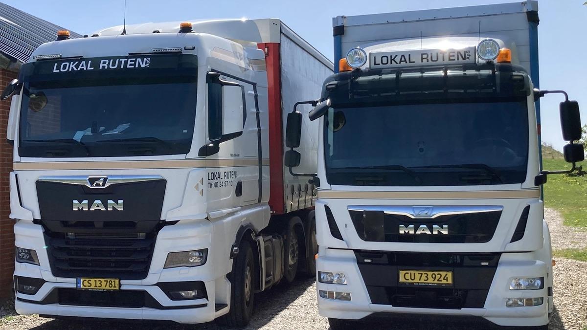 To lastbiler fra MAN parkeret side om side med teksten "LOKAL RUTEN" på fronten.