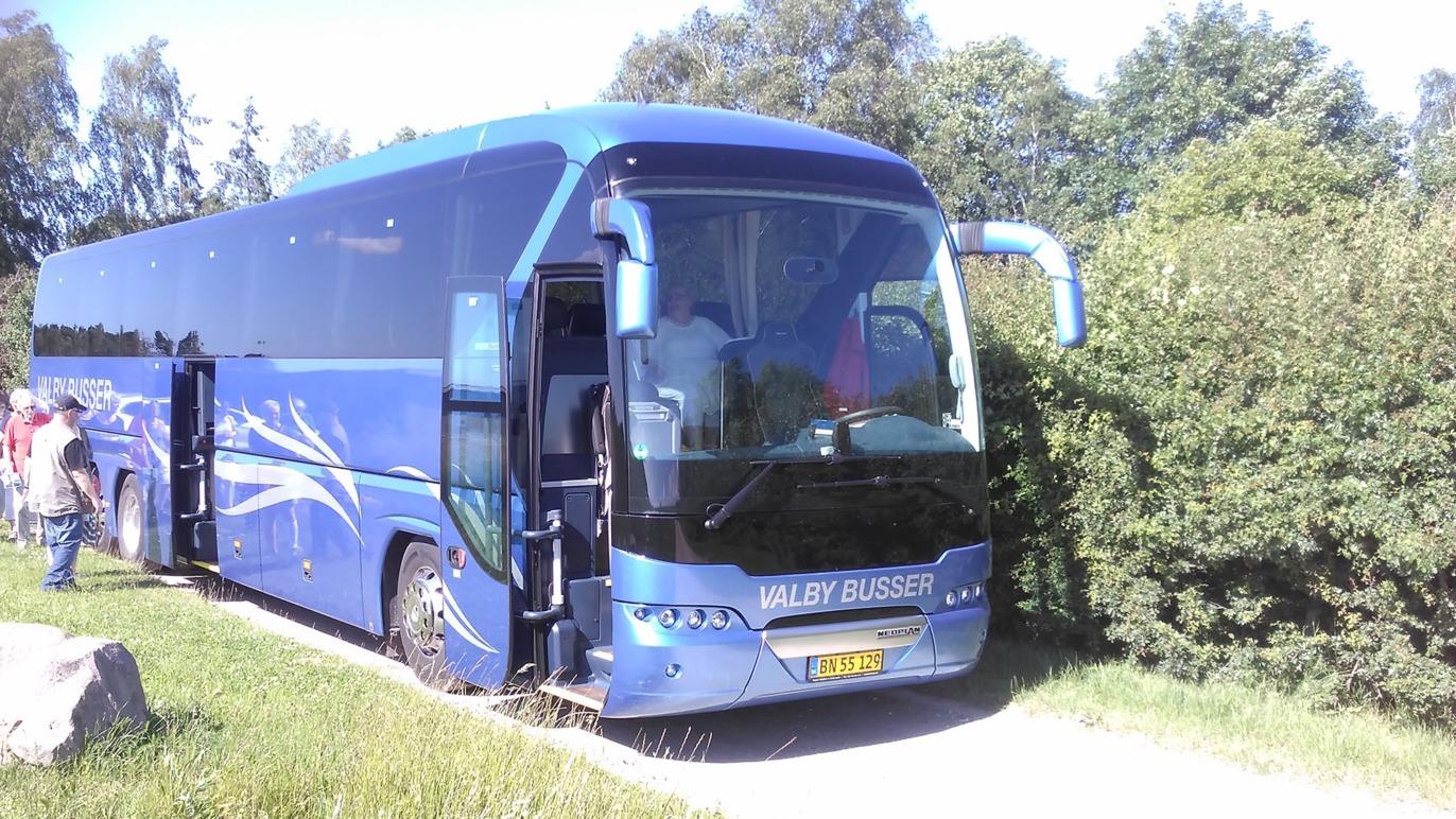 En blå turistbus parkeret ved en vej med busdøren åben og passagerer, der stiger ind og ud.