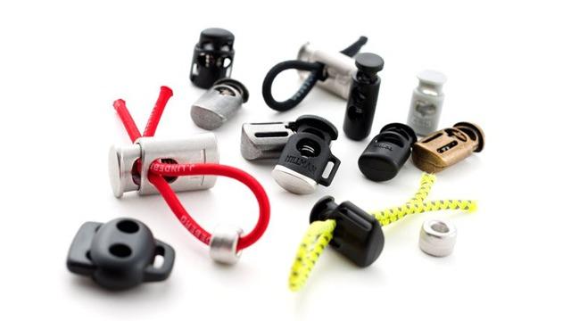 Forskellige typer af snoreholdere og spænder i metal og plastik med farvede snore.