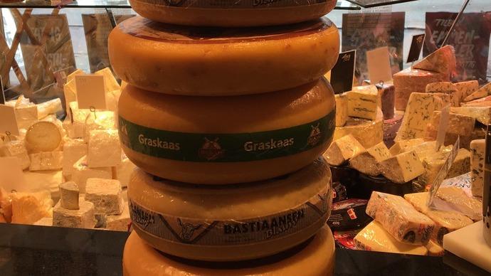 En stak af forskellige oste, herunder Gouda og Grana, præsenteret i en ostebutik.