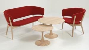 Moderne møbelgruppe med rød sofa og stole samt to runde borde i lyst træ.