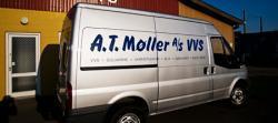 En sølvfarvet varevogn med teksten "A.T. Møller A/S VVS" står parkeret ved en bygning.