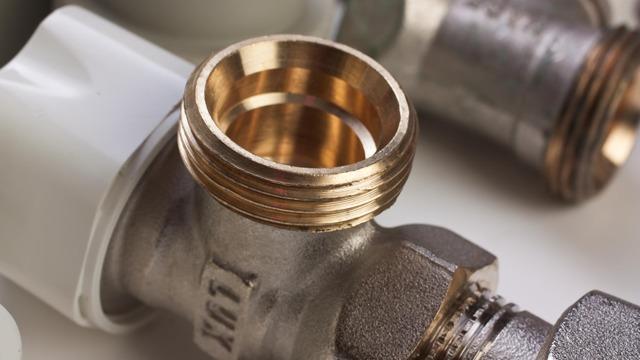 Detaljeret billede af metalrør og fittings til VVS-installationer med messinggevind.