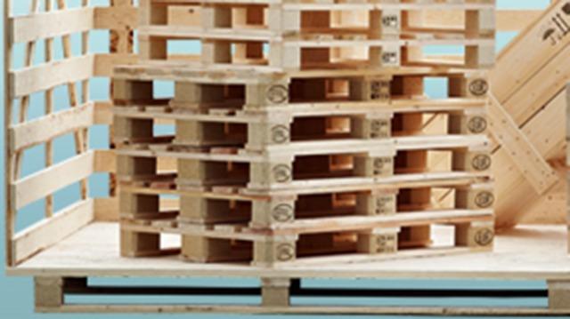 Stabel af træpaller på en palletrailer med en blå baggrund.