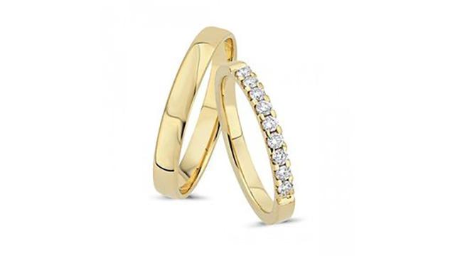 To smukke guld vielsesringe, den ene med diamanter, der glitrer i lyset.