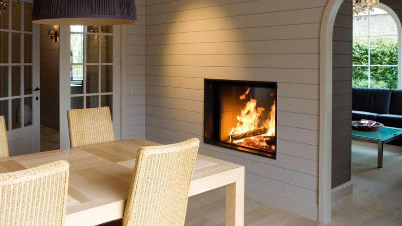 Moderne stue med en pejs, et lyst spisebord og kurvestole i en indbydende atmosfære.
