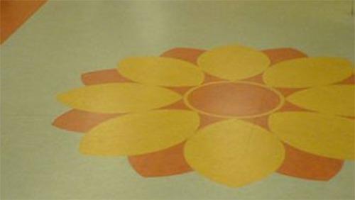 Blomsterdesign i gule og orange nuancer på en farverig gulvbelægning.