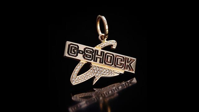 Guld G-SHOCK vedhæng med glitrende detaljer på sort baggrund.