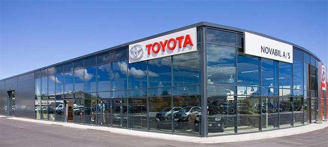 Toyota bilforhandler med store glasvinduer og biler udstillet foran bygningen.
