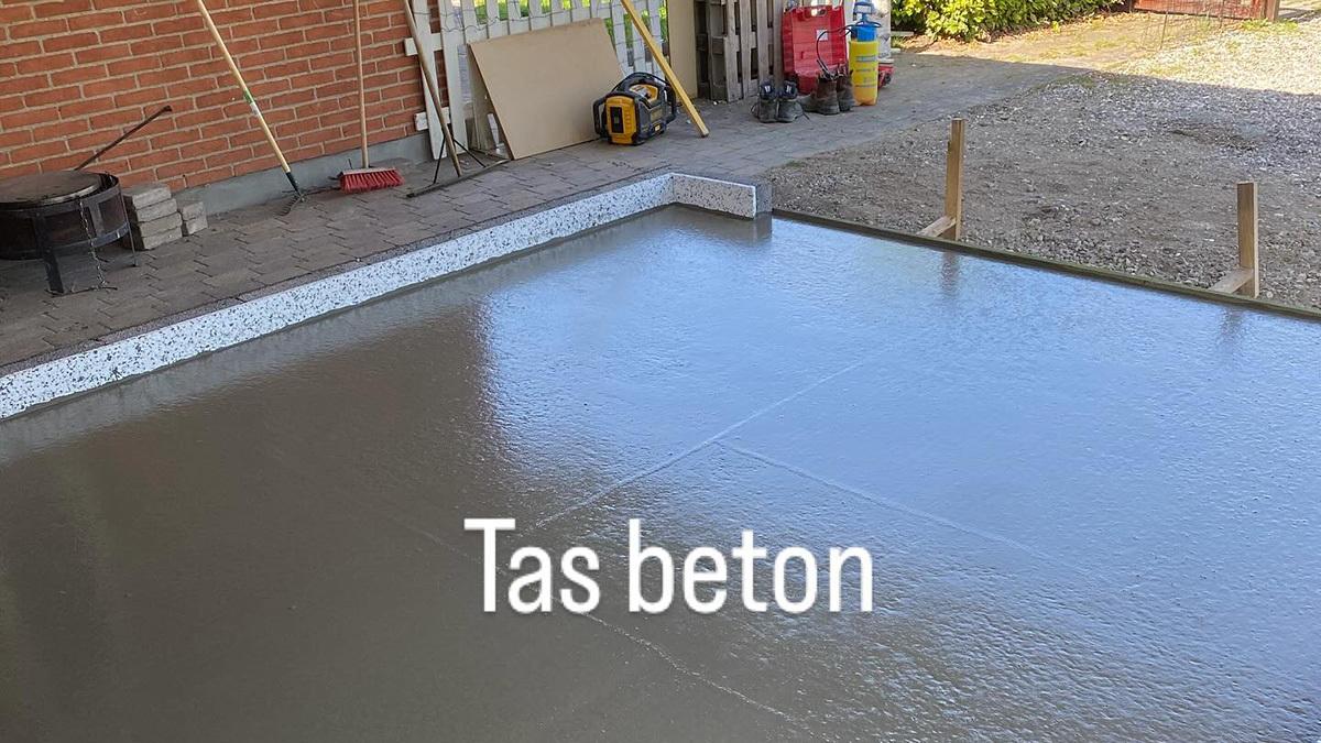 En ny betonplade, der er blevet jævnet og glattet, ligger klar til at hærde i en byggeplads.