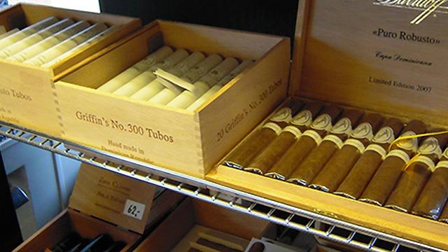 Kasser med cigarer i en butik, herunder "Quality No. 200 Tubos" og "Puro Rebonato" i trææsker.
