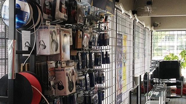 En butiksvæg med forskellige hovedtelefoner og tilbehør hængende på udstillingsstativer.