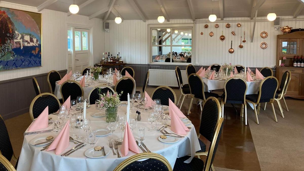 Elegant festlokale med dækkede borde, lyserøde servietter og smukke dekorationer til en fest.