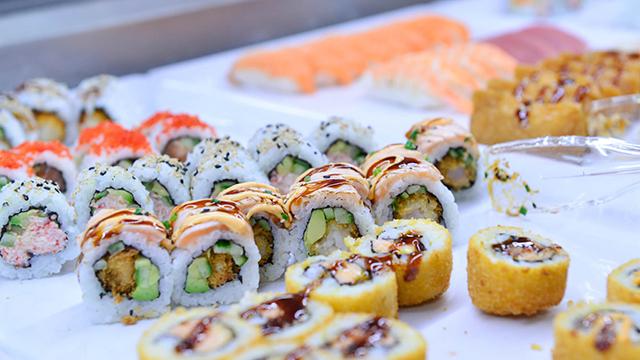 Forskellige typer sushi, herunder maki, nigiri og tempura, præsenteret på en hvid plade.