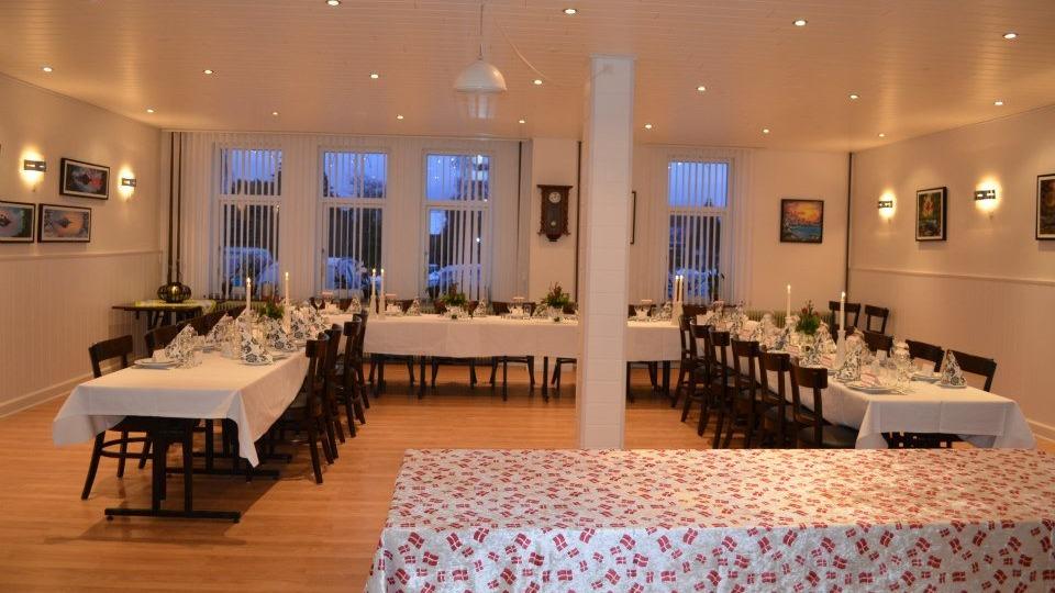 En elegant spisestue med dækkede borde, stearinlys og kunstværker på væggene, klar til fest.